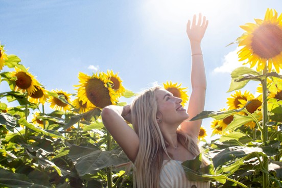 Woman standing in a field of tall sunflowers https://unsplash.com/@courtneymcook