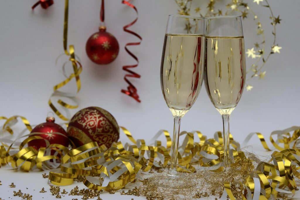 Champagne filled glasses sitting among gold ribbons and red baubles