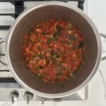 Tomato jam simmering in a stainless steel pot on a gas stove