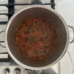 Tomato jam in a stainless steel pot on a gas stove, with liquid reduced, ready to bottle