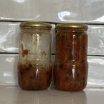 The final result: Tomato jam in 2 glass jars sitting on a kitchen bench