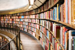 Curved balcony with wooden floors and a steel balustrade. The balcony houses library shelves filled with books.