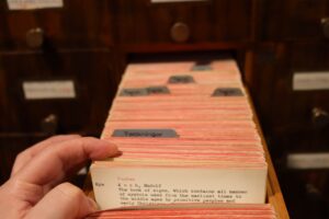 Left hand moving cards in open drawer of library card catalogue