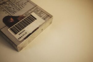 Close-up of a packaged Korean cassette tape with a barcode label reading ‘976HJ3315’ and Korean text ‘장필순-어느새,’ showing part of the cover art and printed text. The Korean text translates to ‘Jang Pil-soon – All of a Sudden’.
